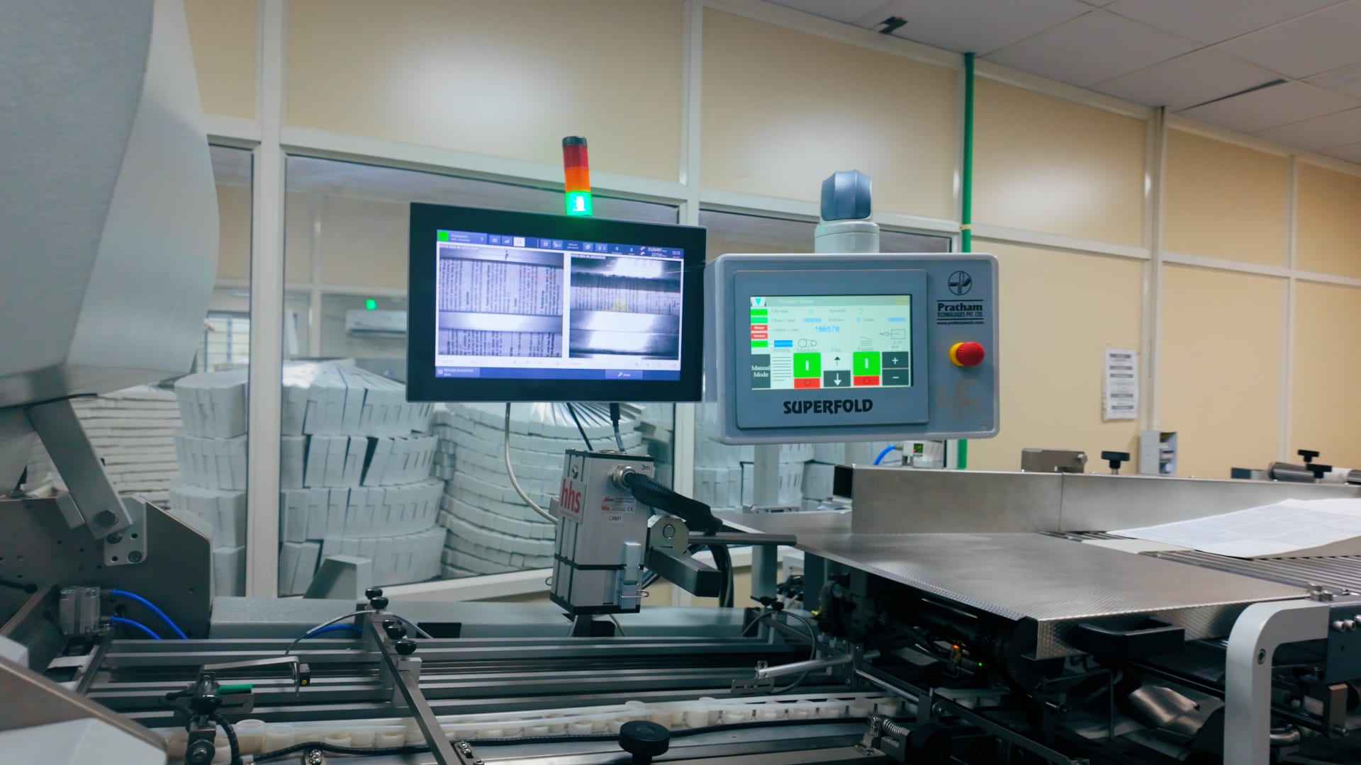 Folding machine control panel with folded pharmaceutical literature stacked in the background